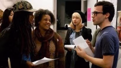 The image is people talking to each other. Some people have paper in their hands.