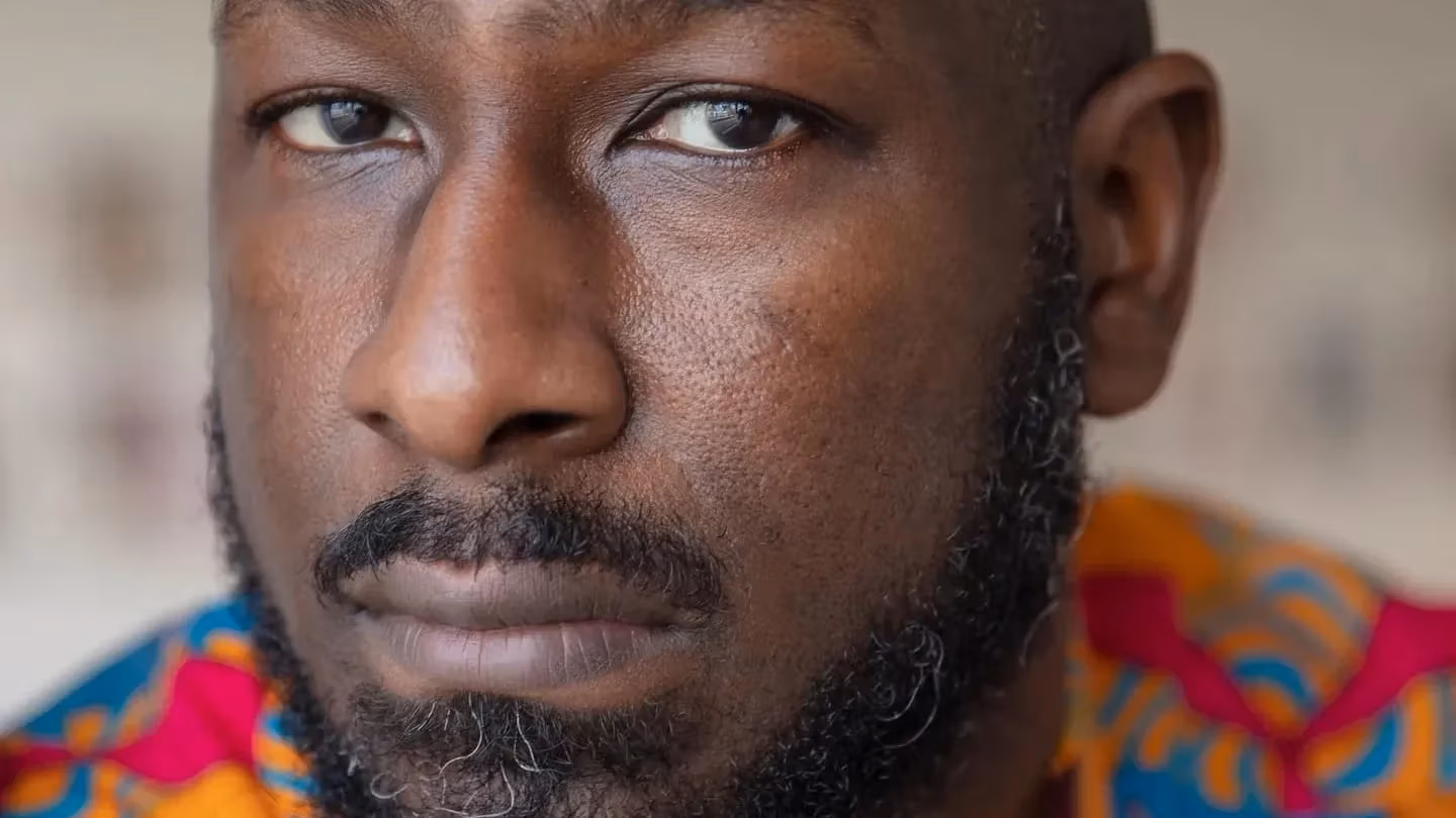 Image of a man looking pensively at the camera with a colorful shirt on 