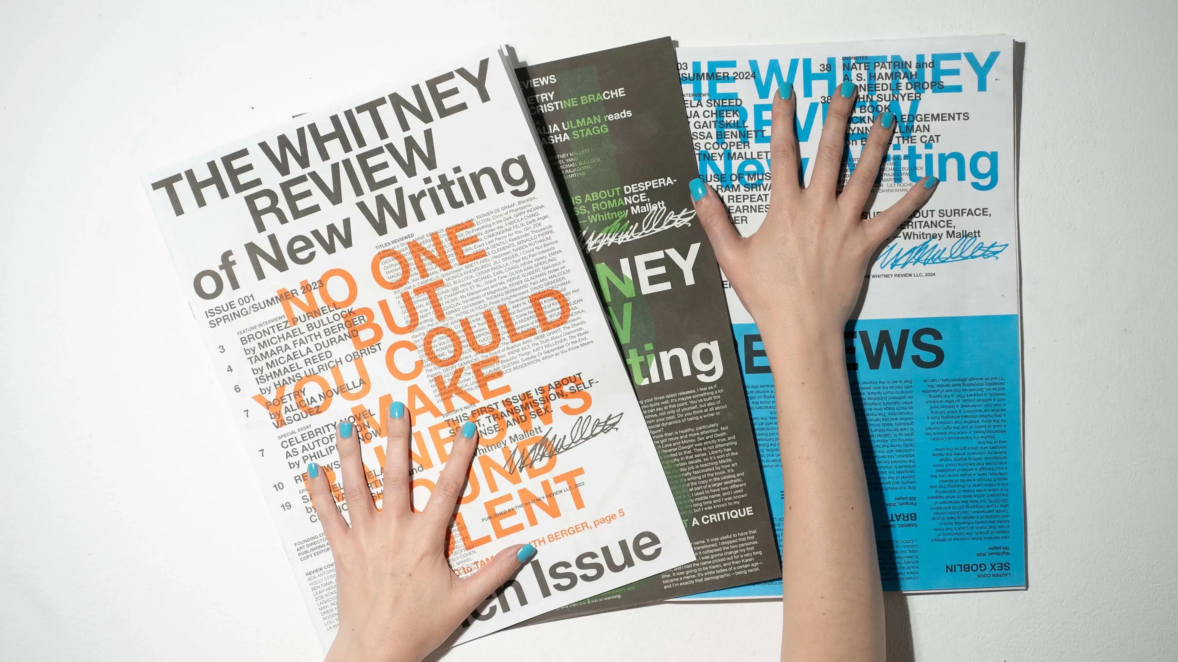 Issues of The Whitney Review with hands on top of them
