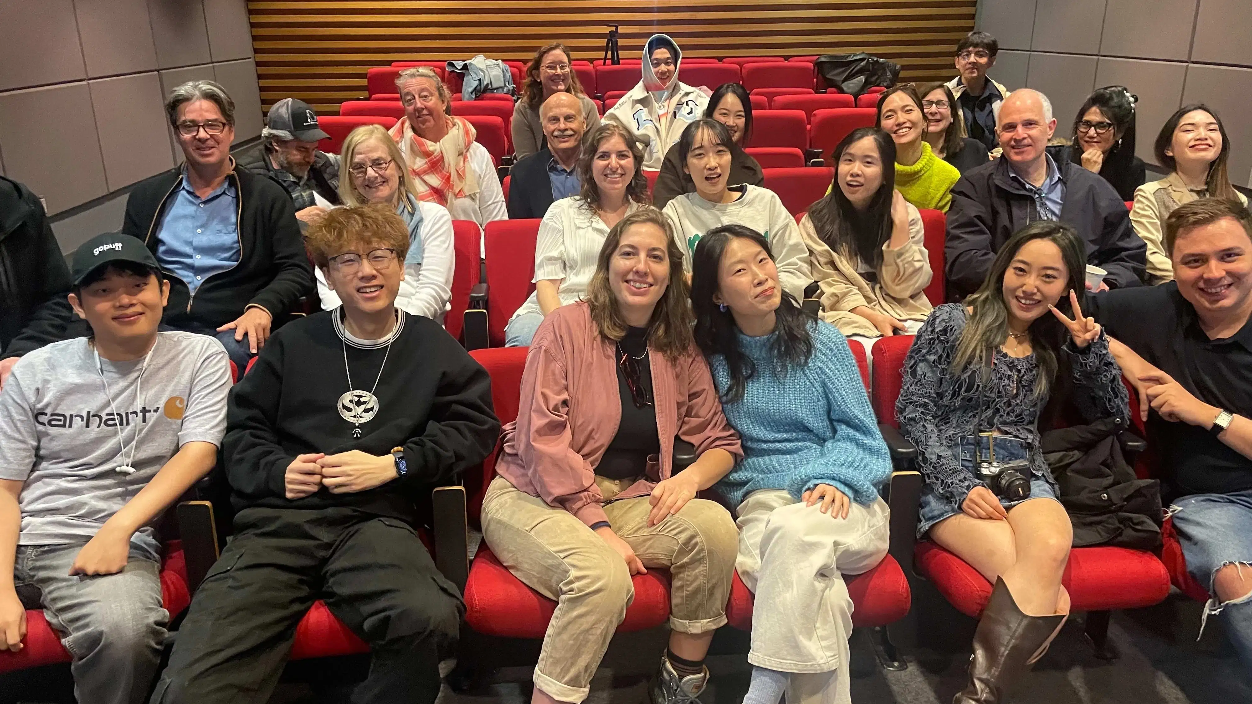 Photo of students and faculty seated in auditorium, smiling.