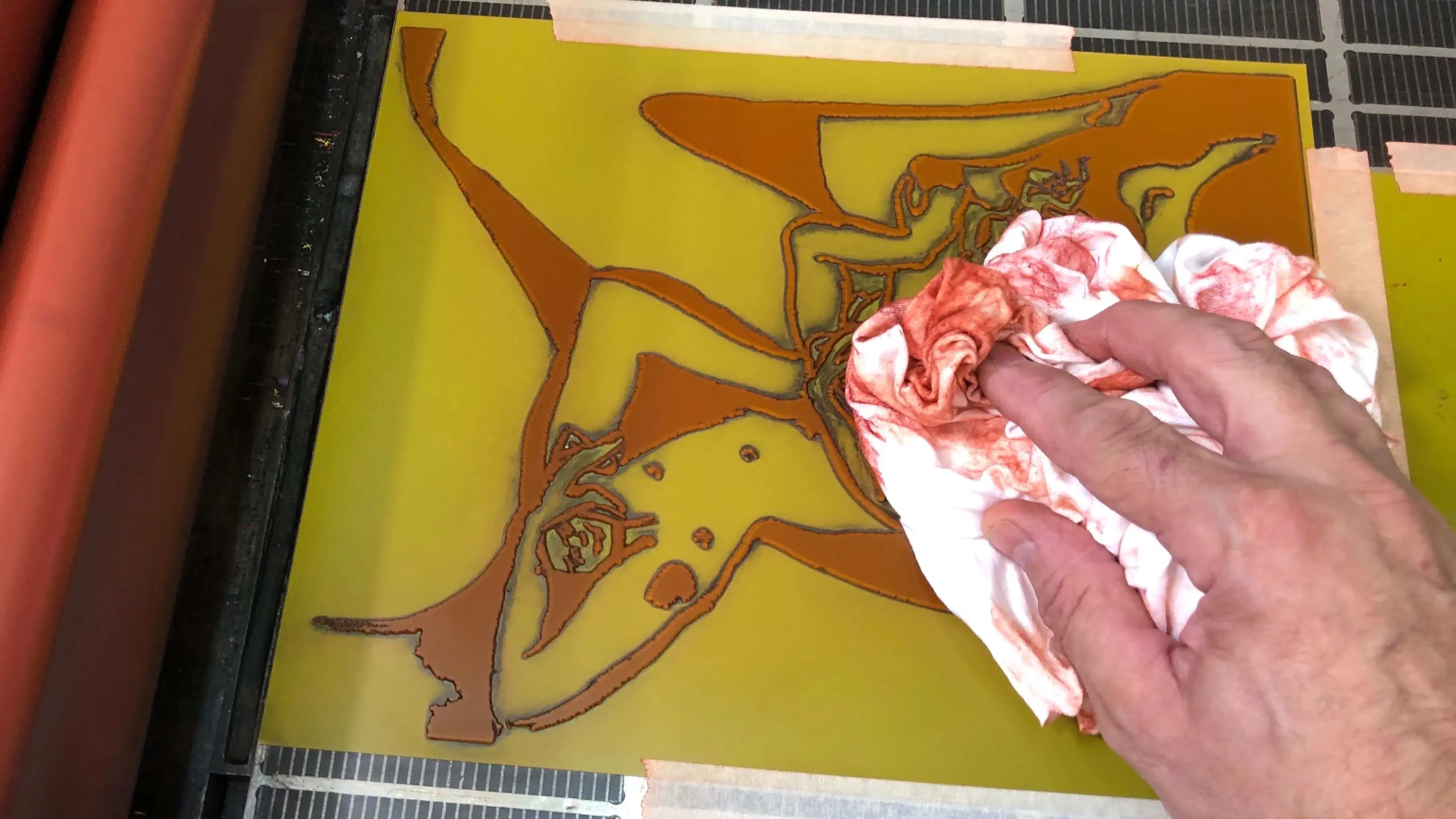 Photograph of a hand cleaning a letterpress plate.