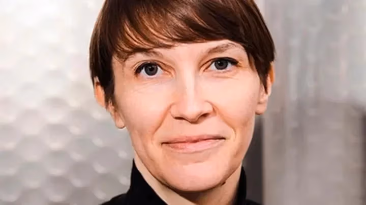 a person with short hair and a black turtleneck look ahead