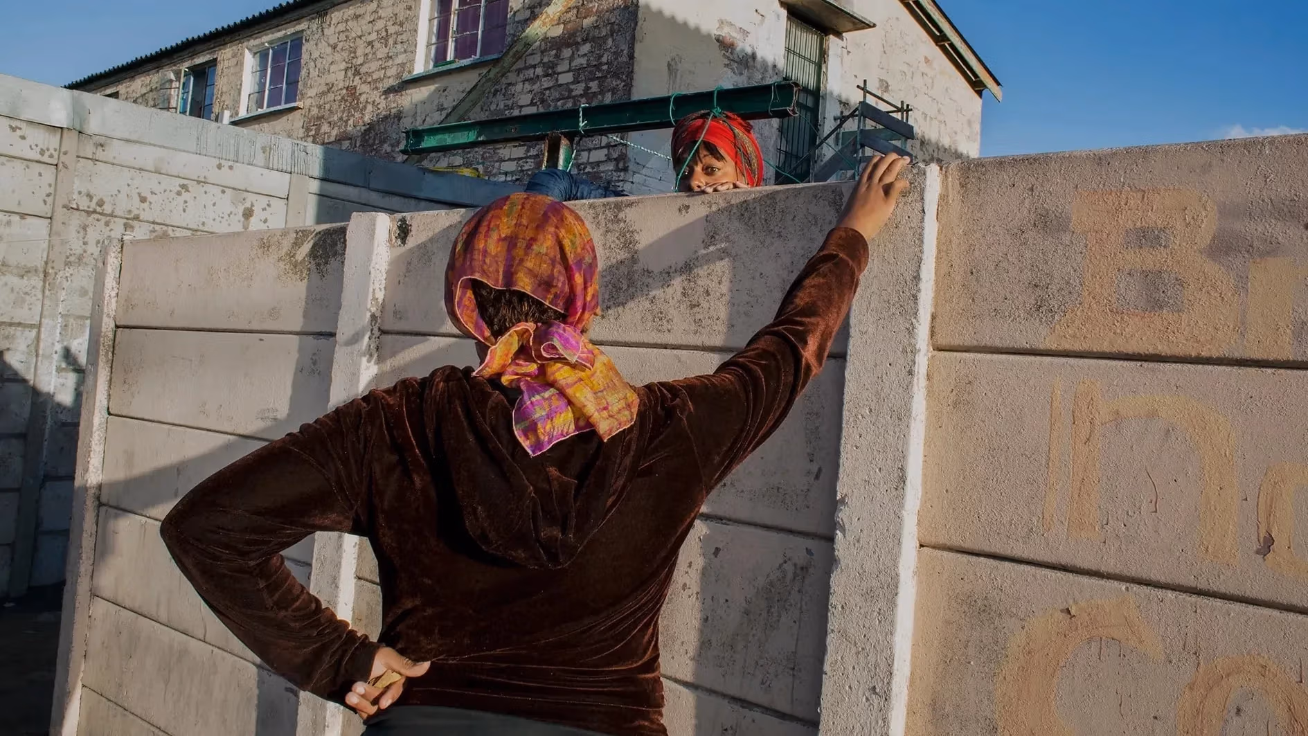 Two women speaking over a concrete wall. 