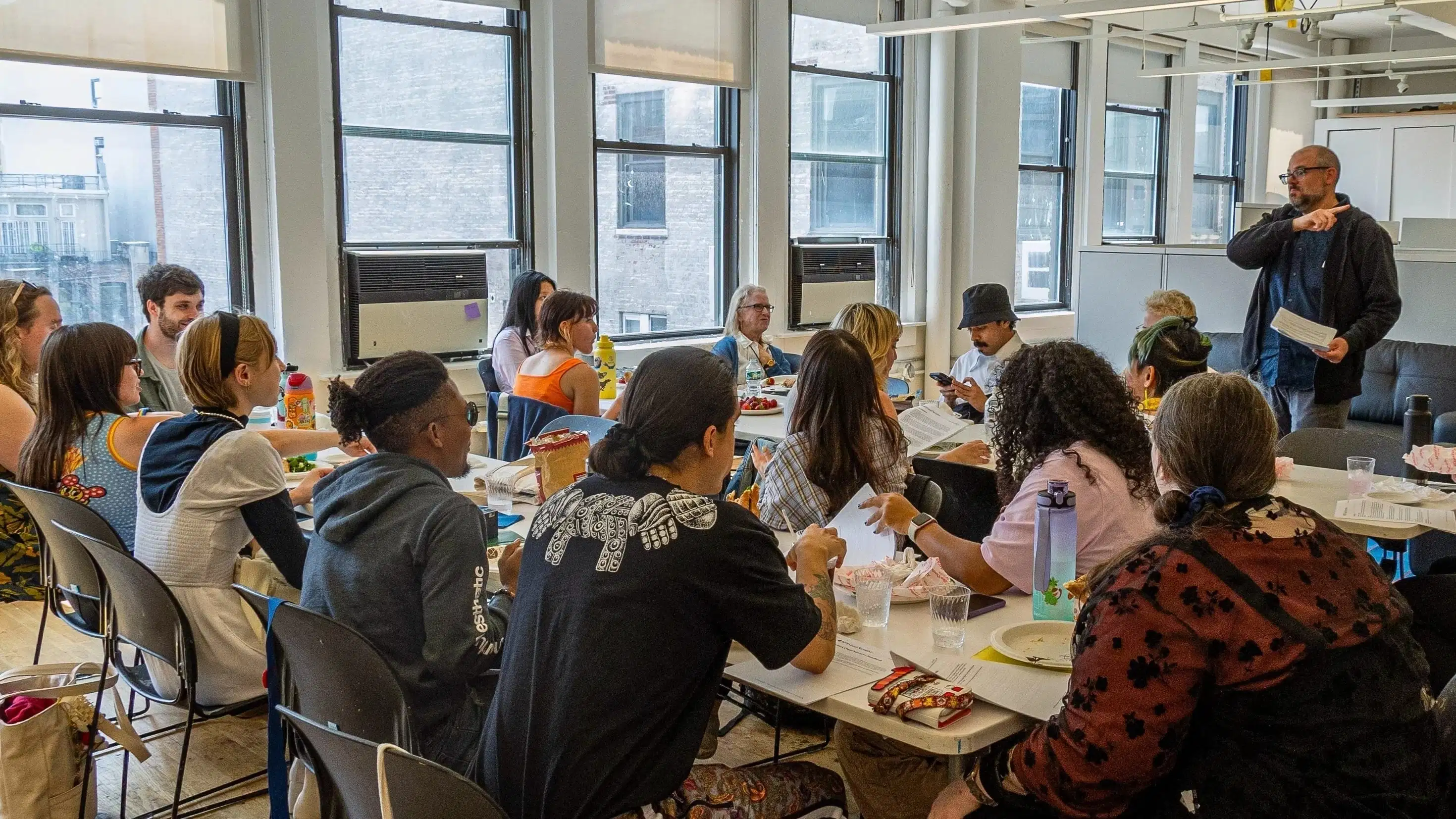 Photo of students sitting around tables in a classroom.