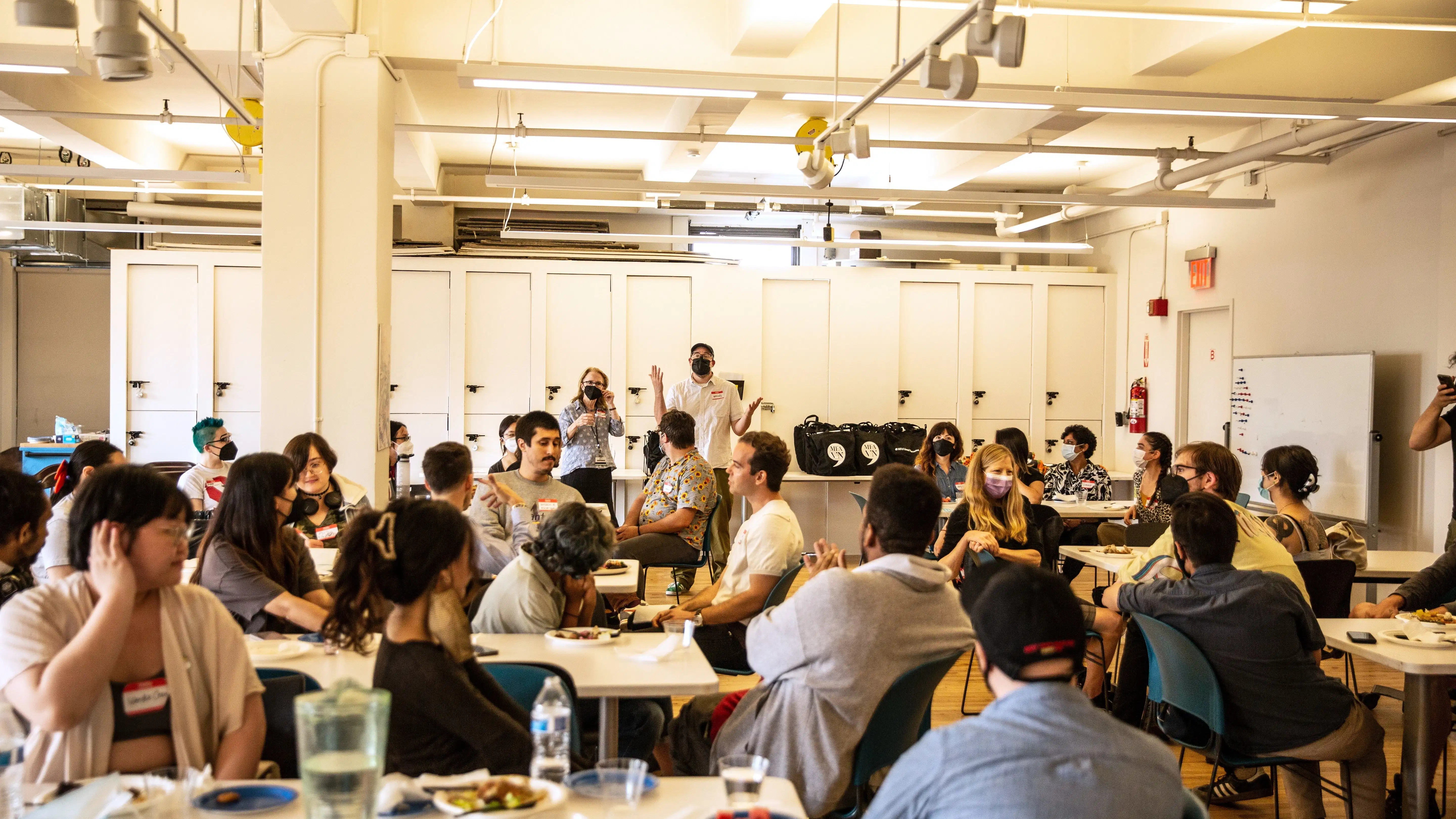 a group of people sit in a classroom while two people at the front lead instruction