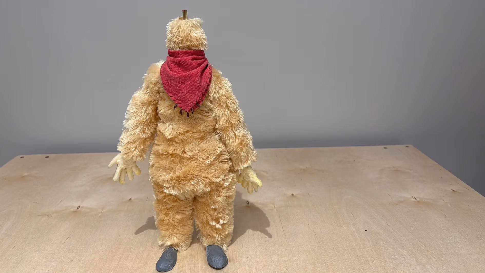 A furry puppet standing up with a red handkerchief on its neck