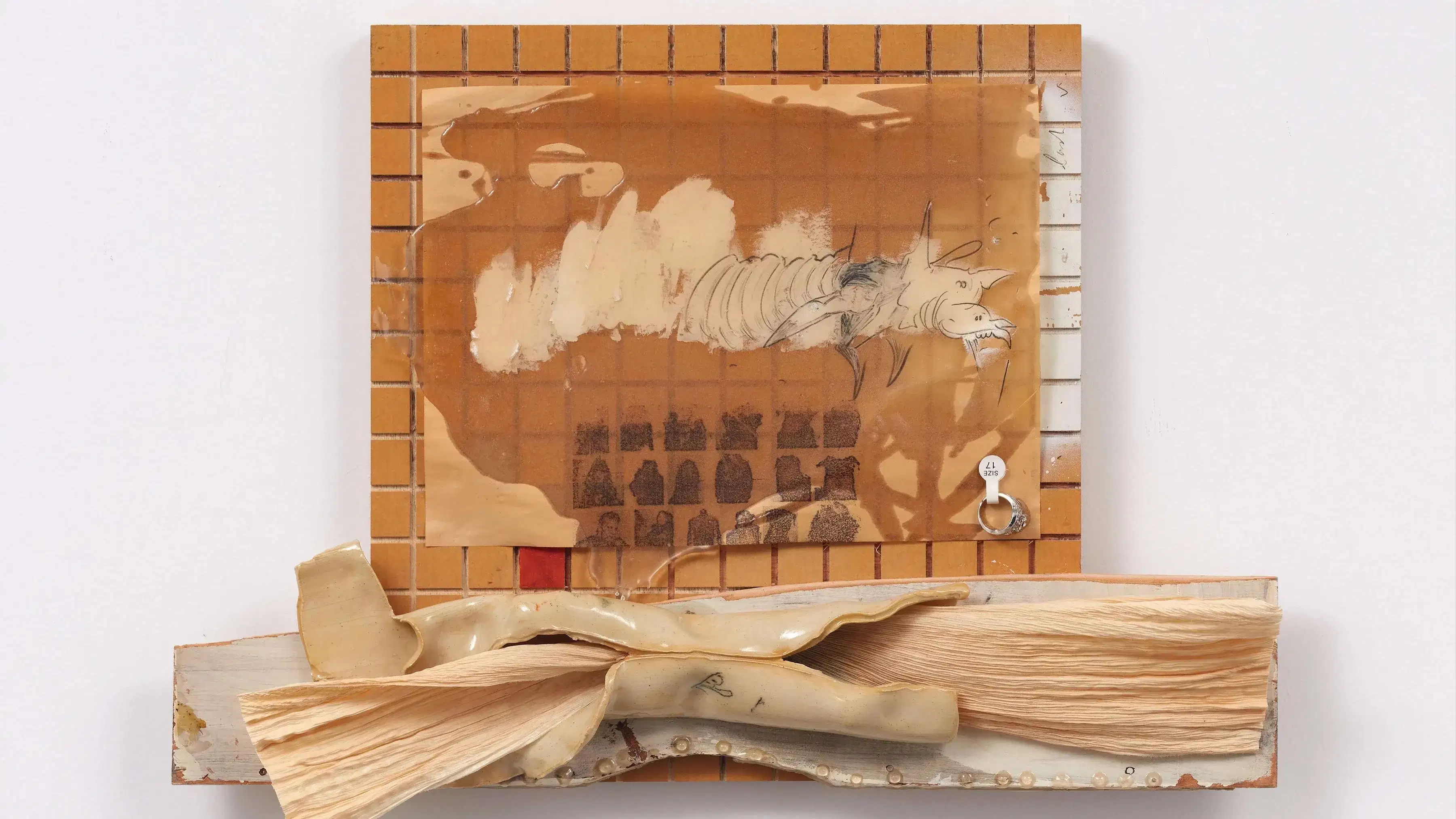 An artwork composed of a tiled orange surface and a transparent sheet of acrylic over it with a drawing on top. Below the tiled plane is another surface with a corn husk  attached