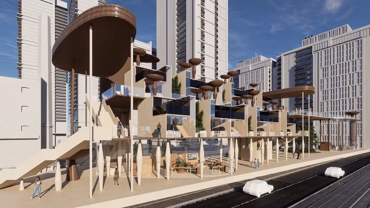 This image shows a futuristic, multi-level architectural structure with sculptural wooden forms and glass-walled spaces set against a backdrop of tall modern buildings. Walkways, terraces, and elevated platforms create an open, layered environment where several people are moving through the space.