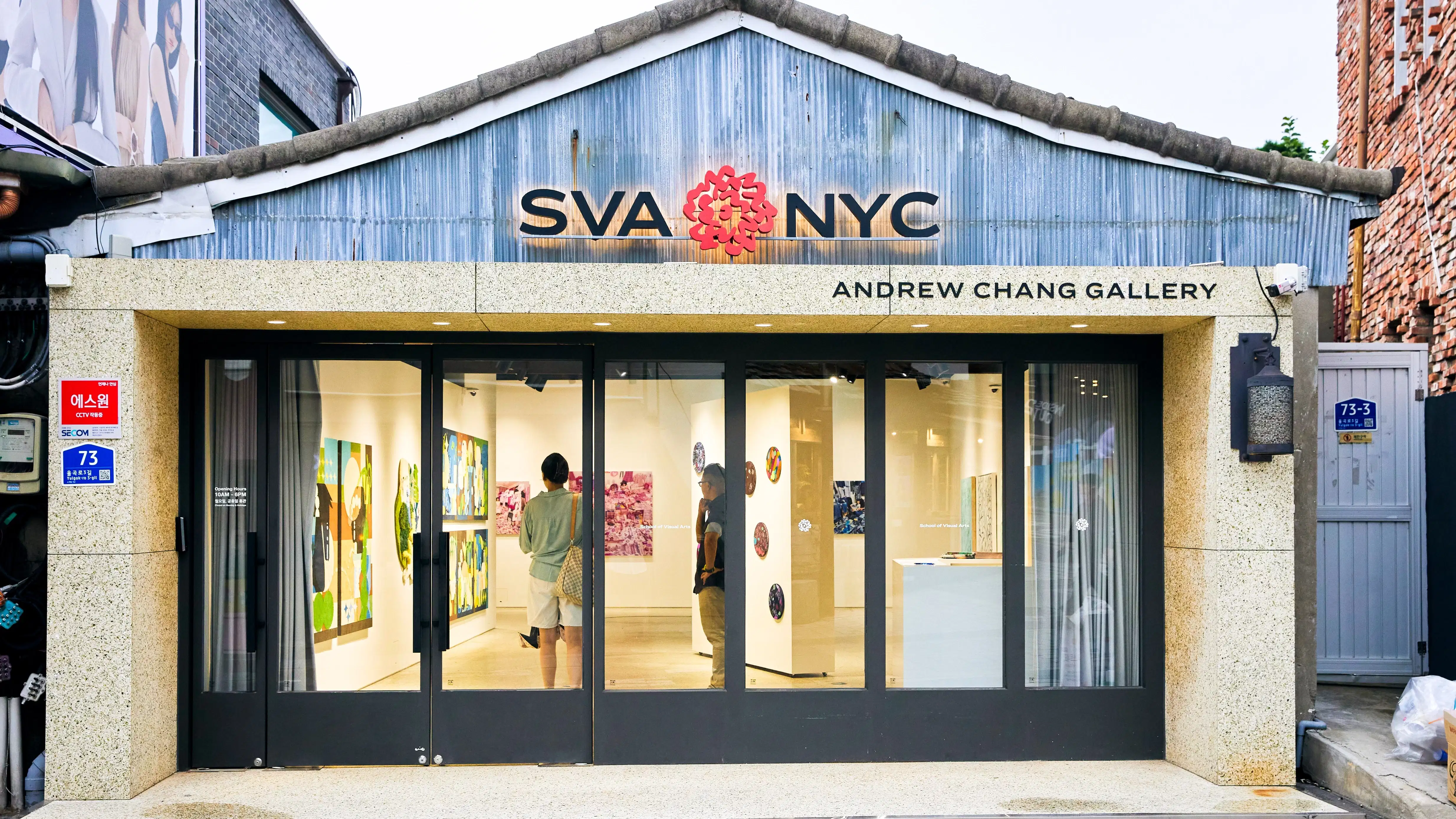 Facade of a brick and mortar gallery with "SVA NYC" insignia and red flower logo and "Andrew Chang Gallery" signs.