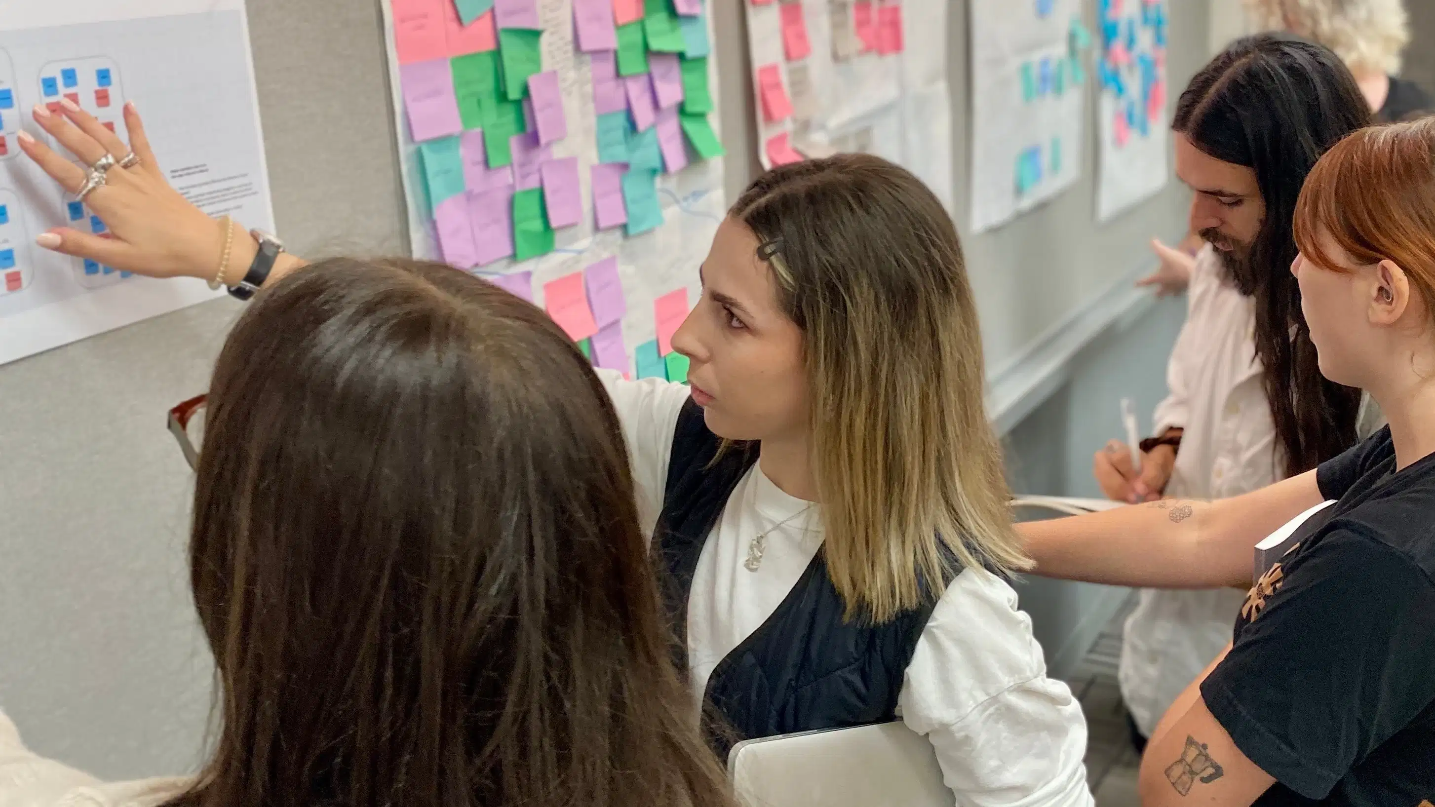 Photograph of four students reviewing work pinned on a bulletin board