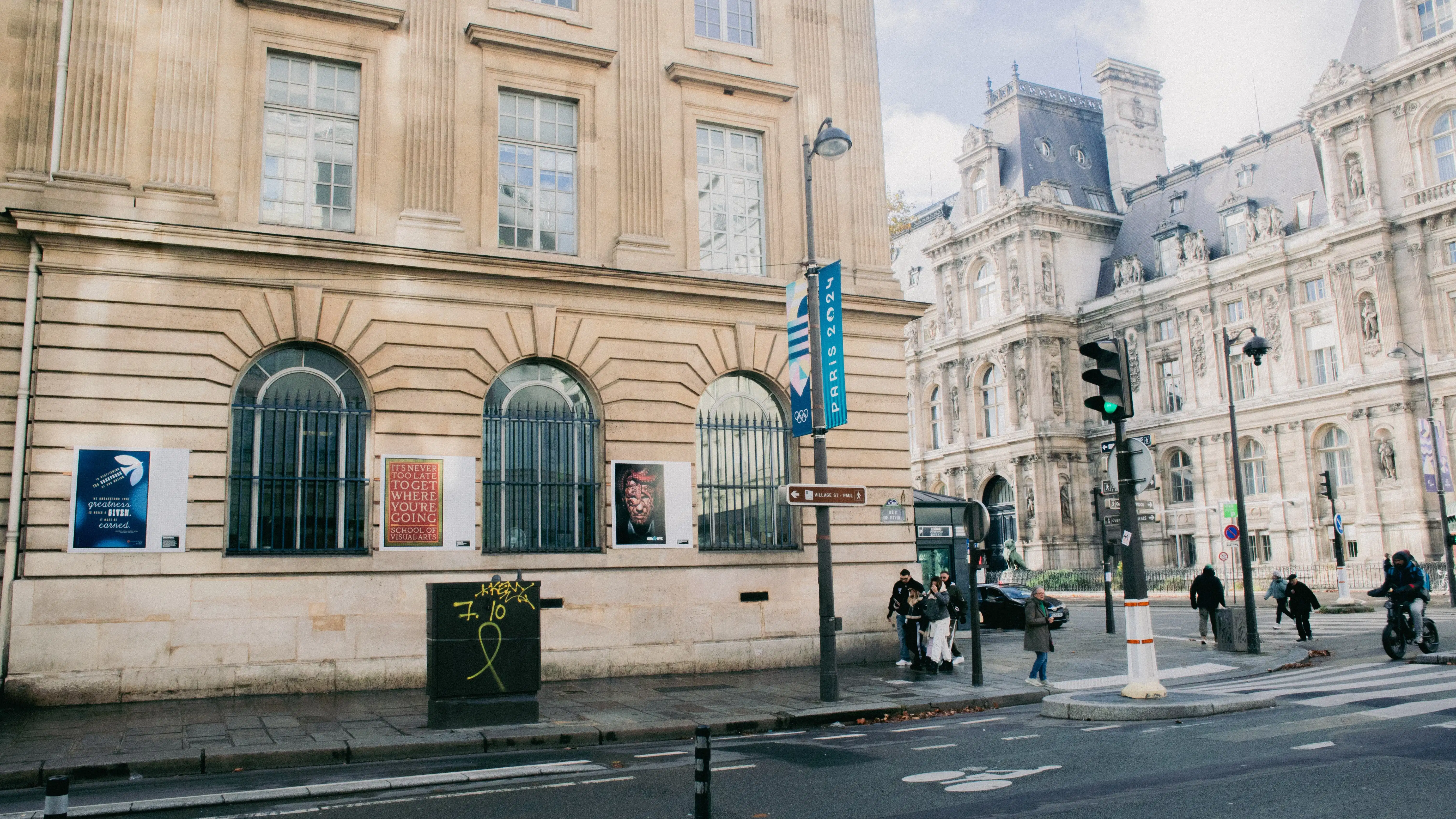 Street view of a building with SVA posters on the side. People are walking on the nearby crosswalk.