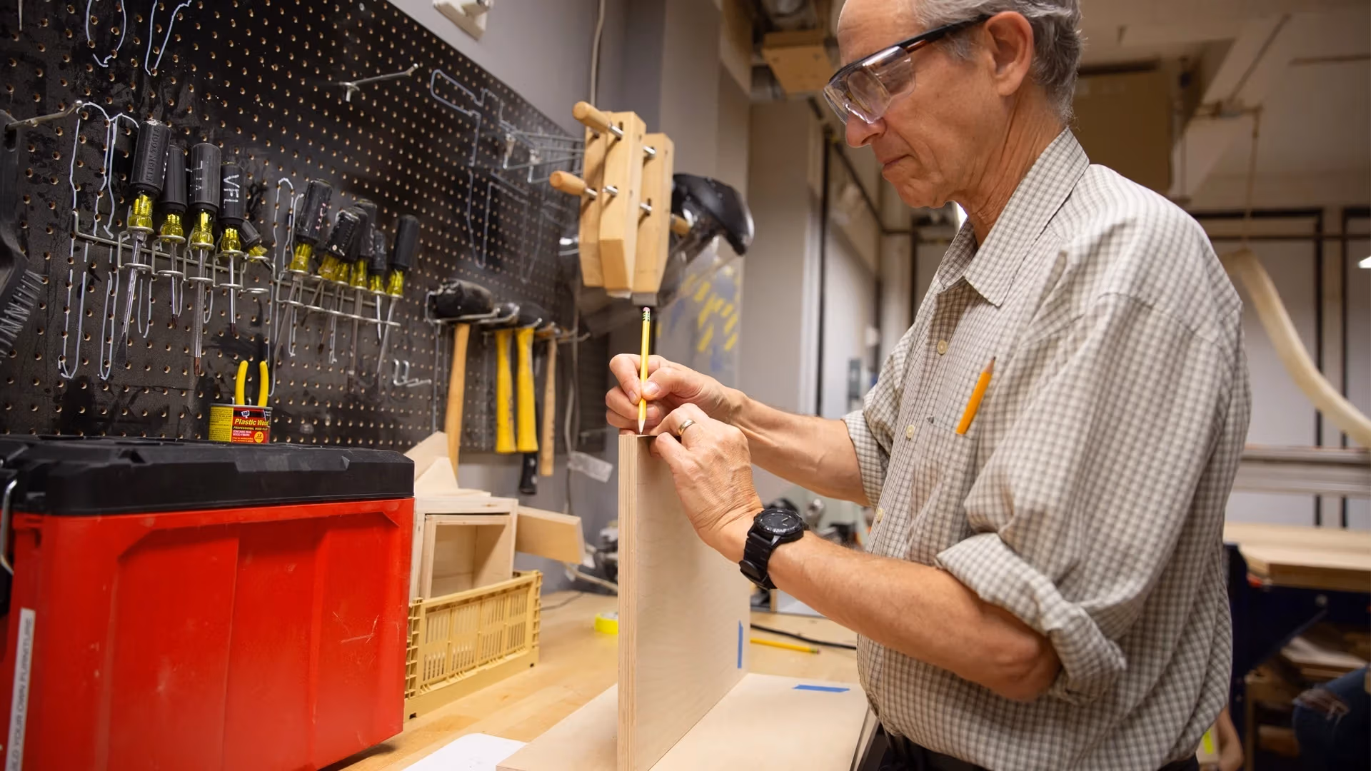 Man drawing on a piece of wood in a woodshop