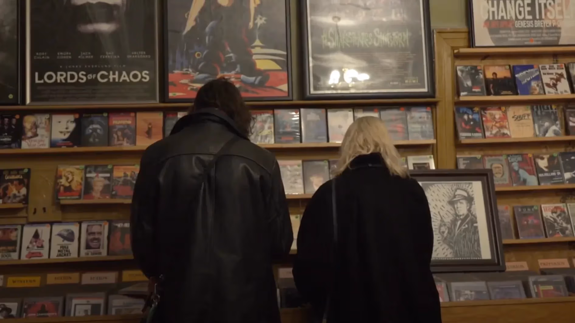Two people, facing away, looking through DVDs on a shelf 