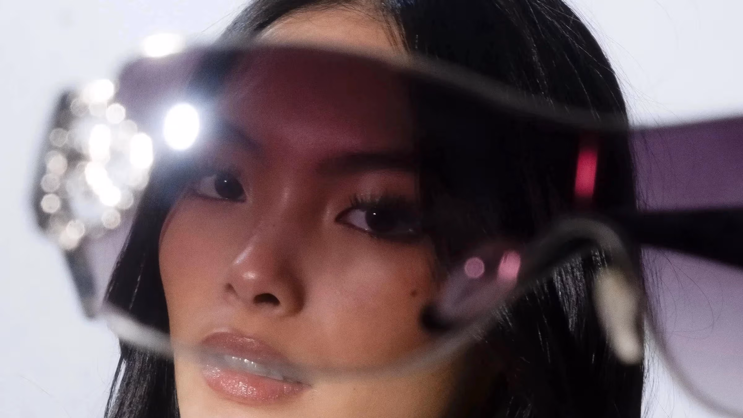 A woman's face peering through glasses 