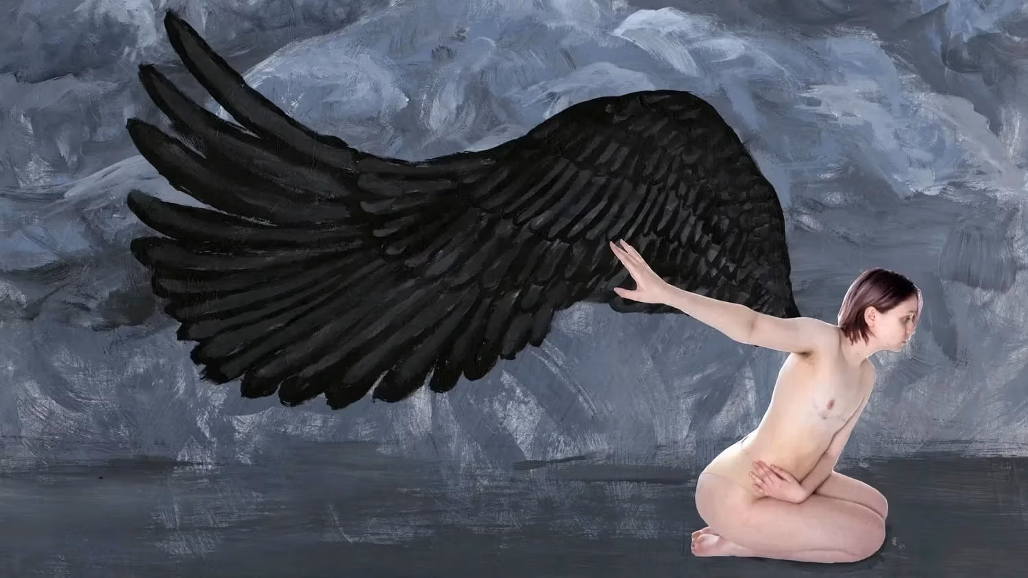 Self-portrait of a person kneeling in a grey painted background with black painted wings. 