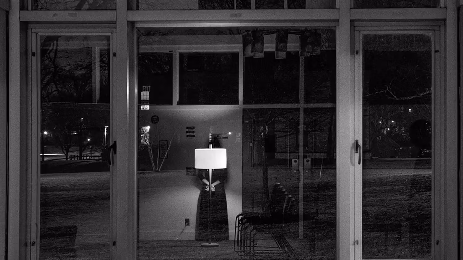 A black and white photo displays reflections in a window and the scenery outside.