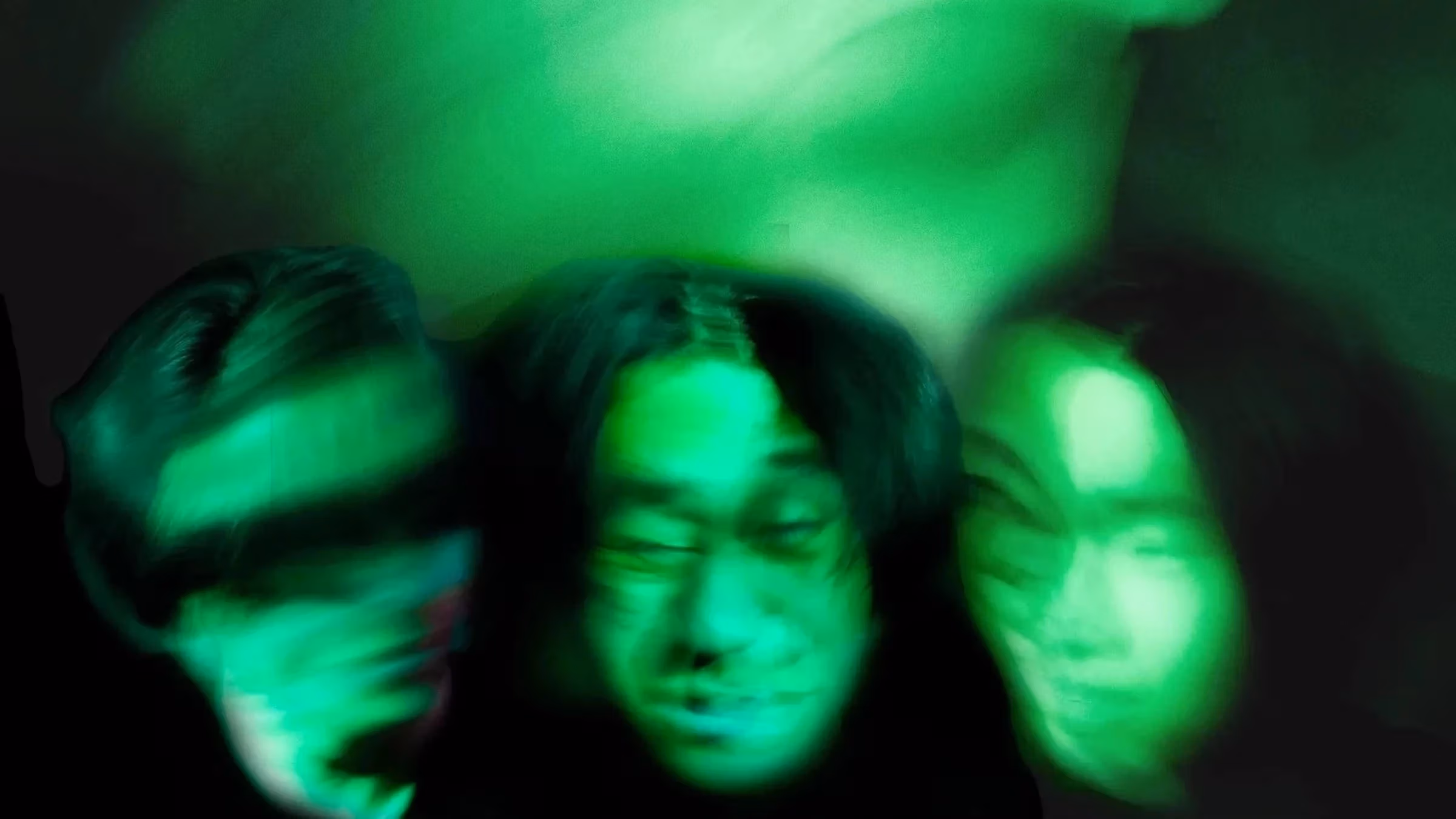 a black and green photo of blurred faces