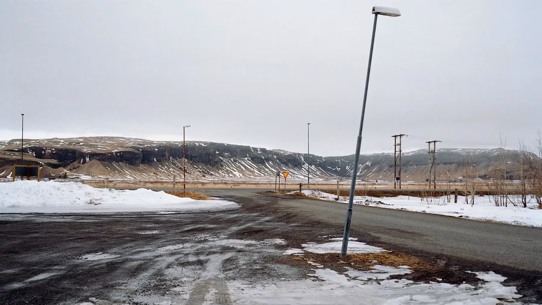 A snowy road with mountains in the background.