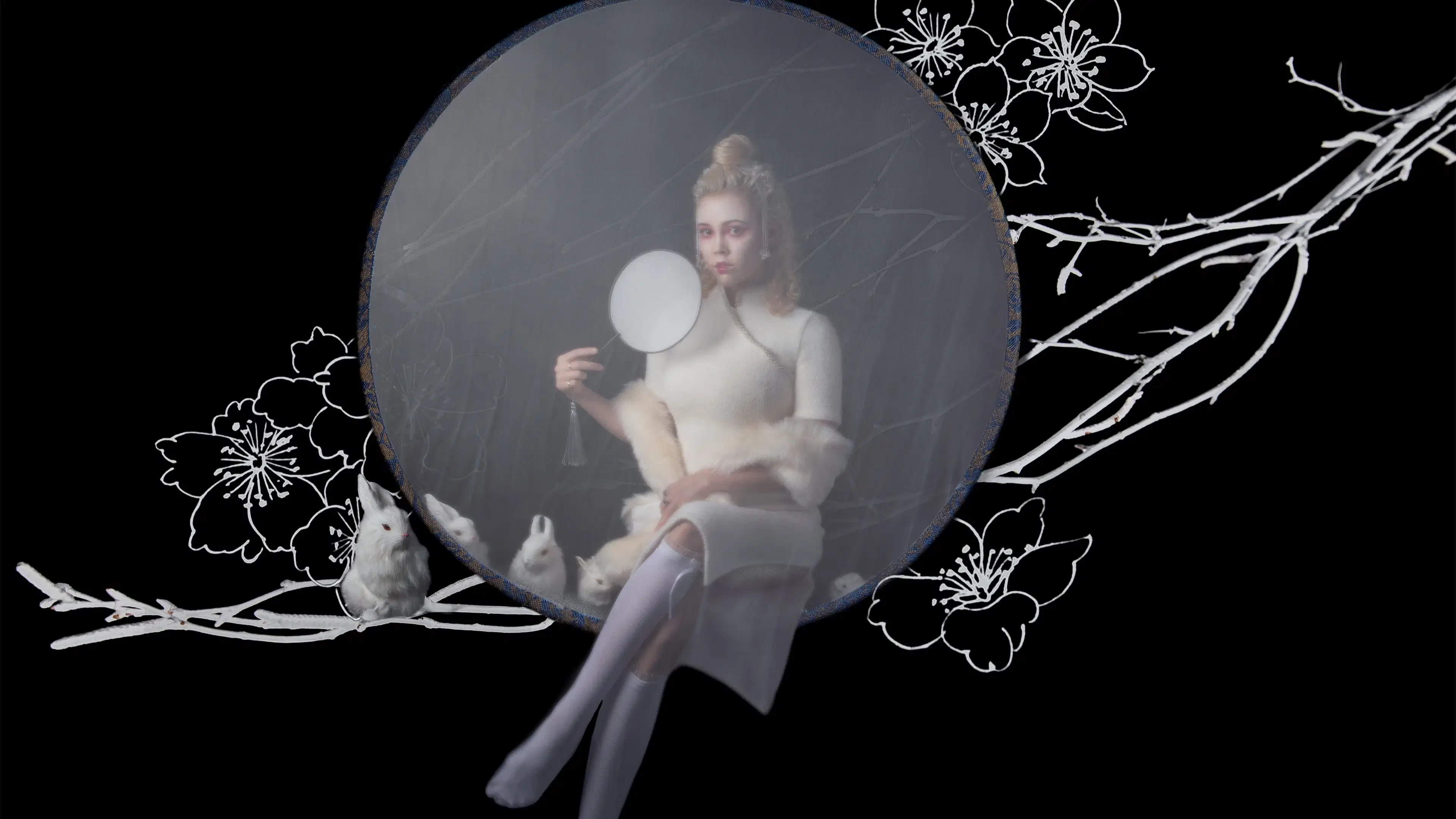 A photograph of a woman with blond hair wearing a white dress and stockings, holding a white circular fan up to her face. Her face is painted white and she is staring at the camera, sitting with her legs crossed. Around her is a gray circle, suspended in front of a white group of branches and white flowers against a black background. Sitting on the branches is a white bunny. Within the gray circle are three more white bunnies.