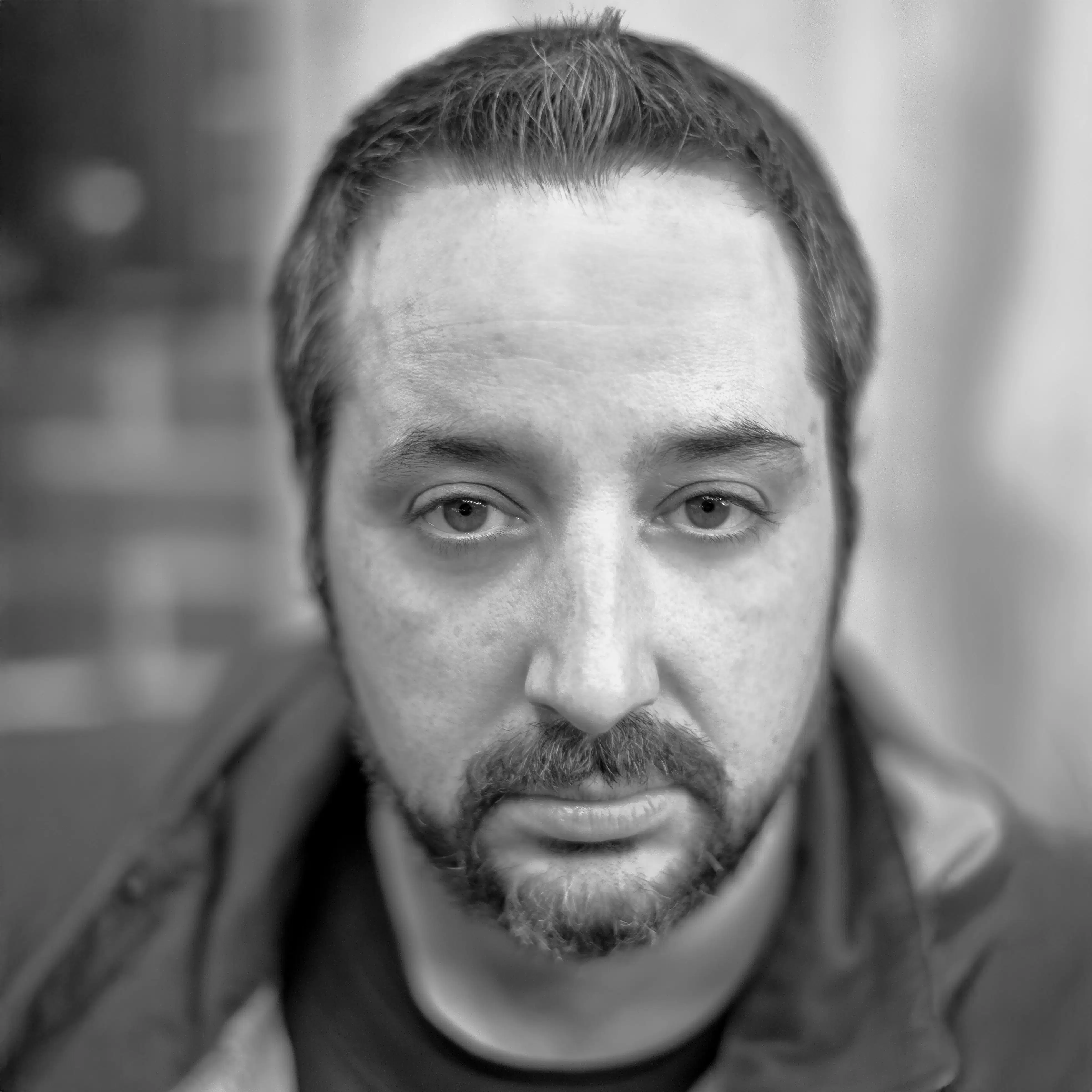 a person with a beard looks into the camera with great intensity.