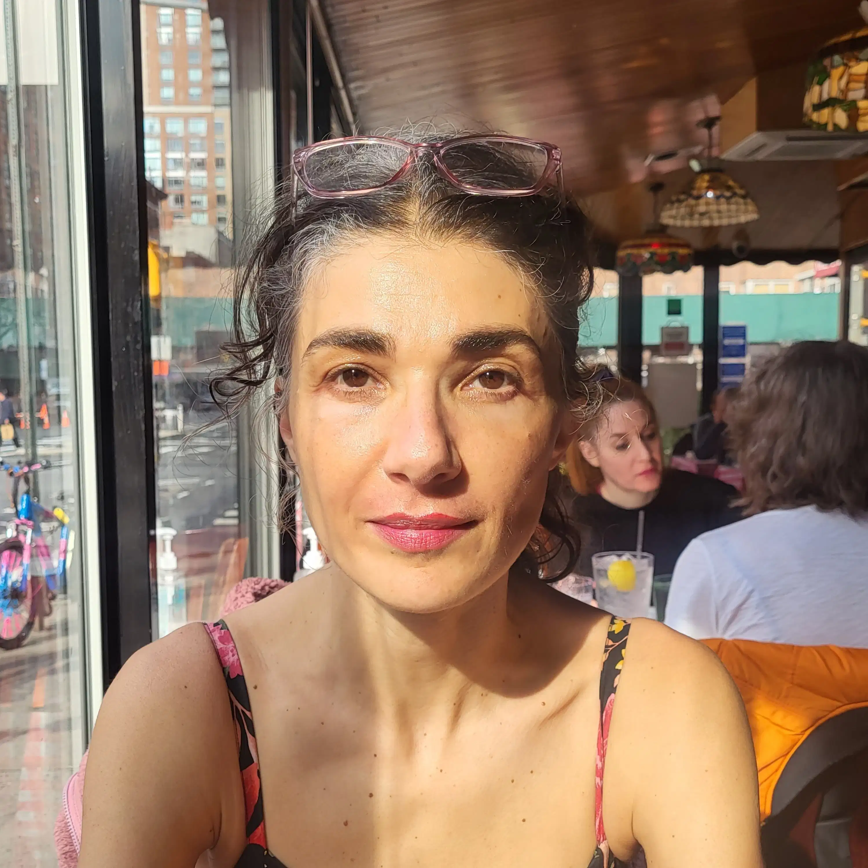 Image of a woman looking into the camera with a pair of glasses on her head.