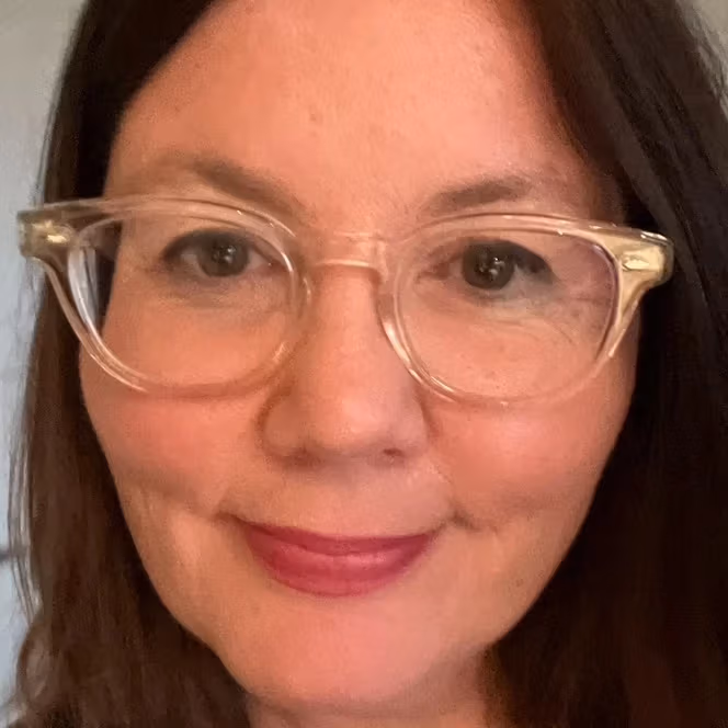 A profile picture of Laura against a white background. Laura is wearing a pair of glasses with a clear frame, and she is smiling to the camera. 