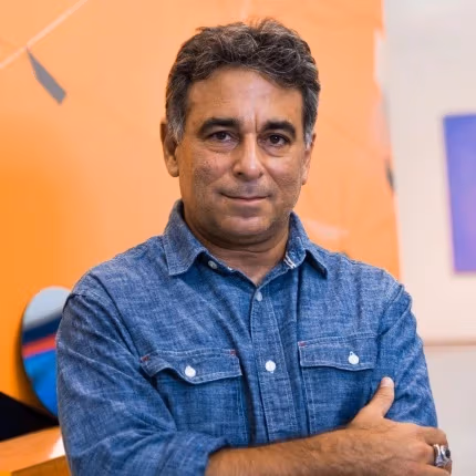 Omar Lopez-Chahoud smiles with arms crossed in a denim shirt