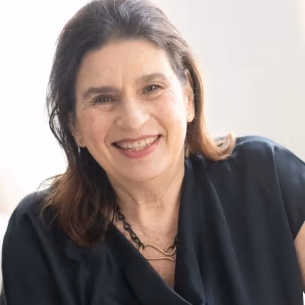 Portrait of Barbara Pollack,  with long brown hair and big smile,  wearing a necklace by Jelena Behrend