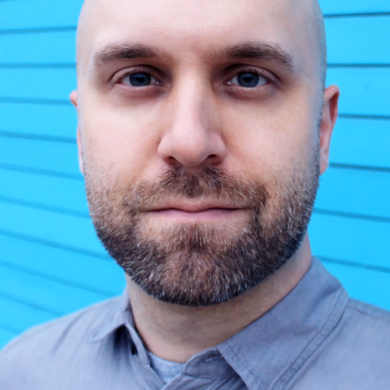 Portrait of Tim Szetela against a blue painted wall