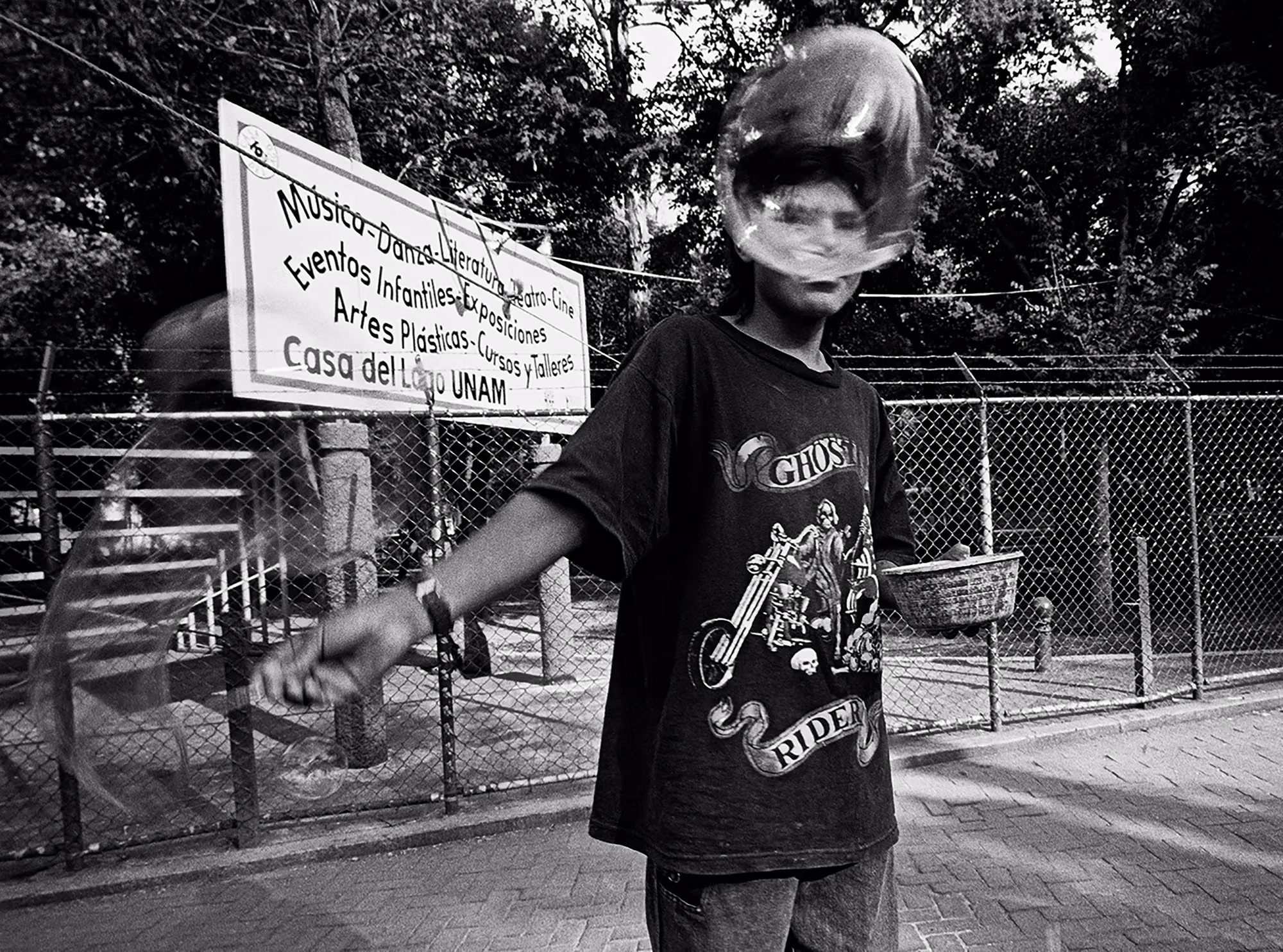Youth making bubbles in a Mexico City park, bubble in front of his face.