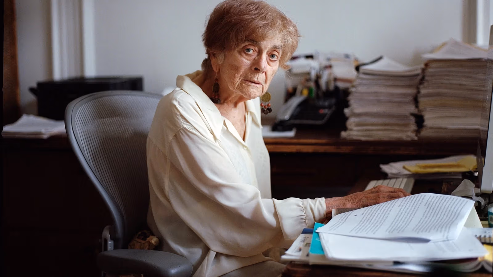 Frances Fox Piven, among piles of papers, looking steadily ahead