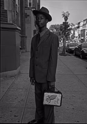 Young black male, in a suit and hat.