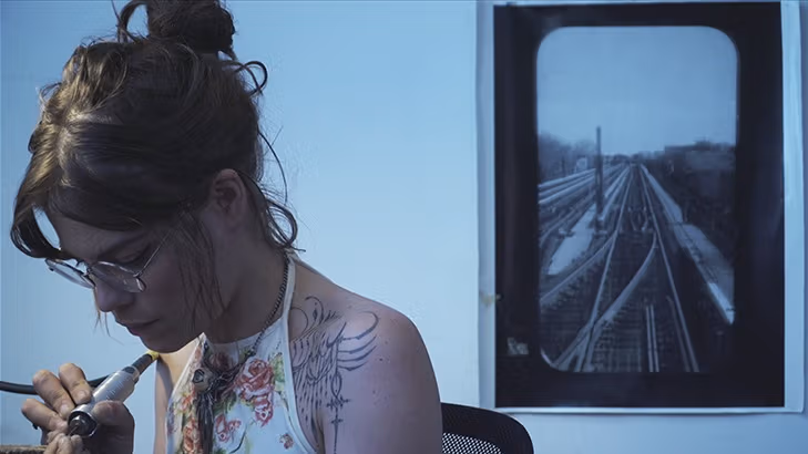A tattoo artist checks out or is cleaning her tool.