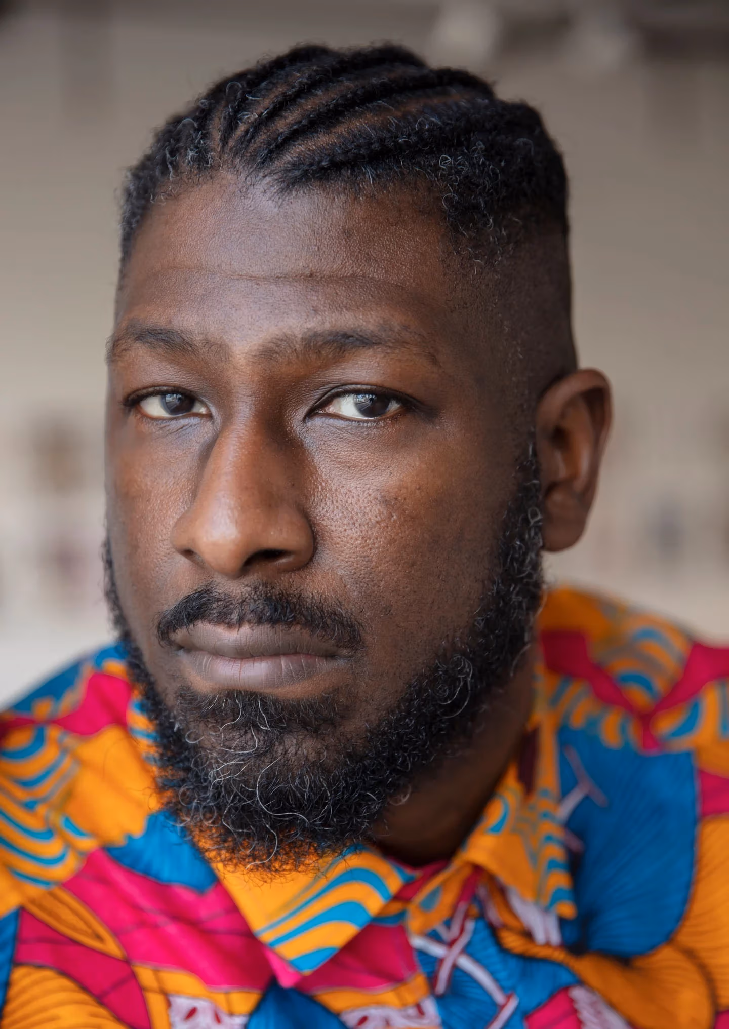 Image of a man looking pensively at the camera with a colorful shirt on 