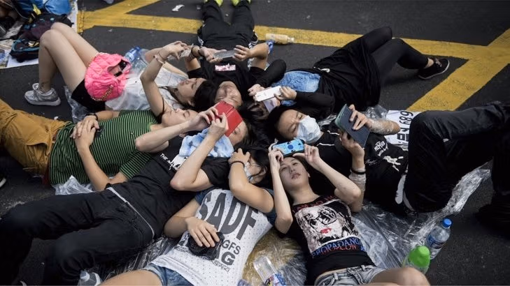 Group of Asian teenagers staring at their smart phones in a circle.