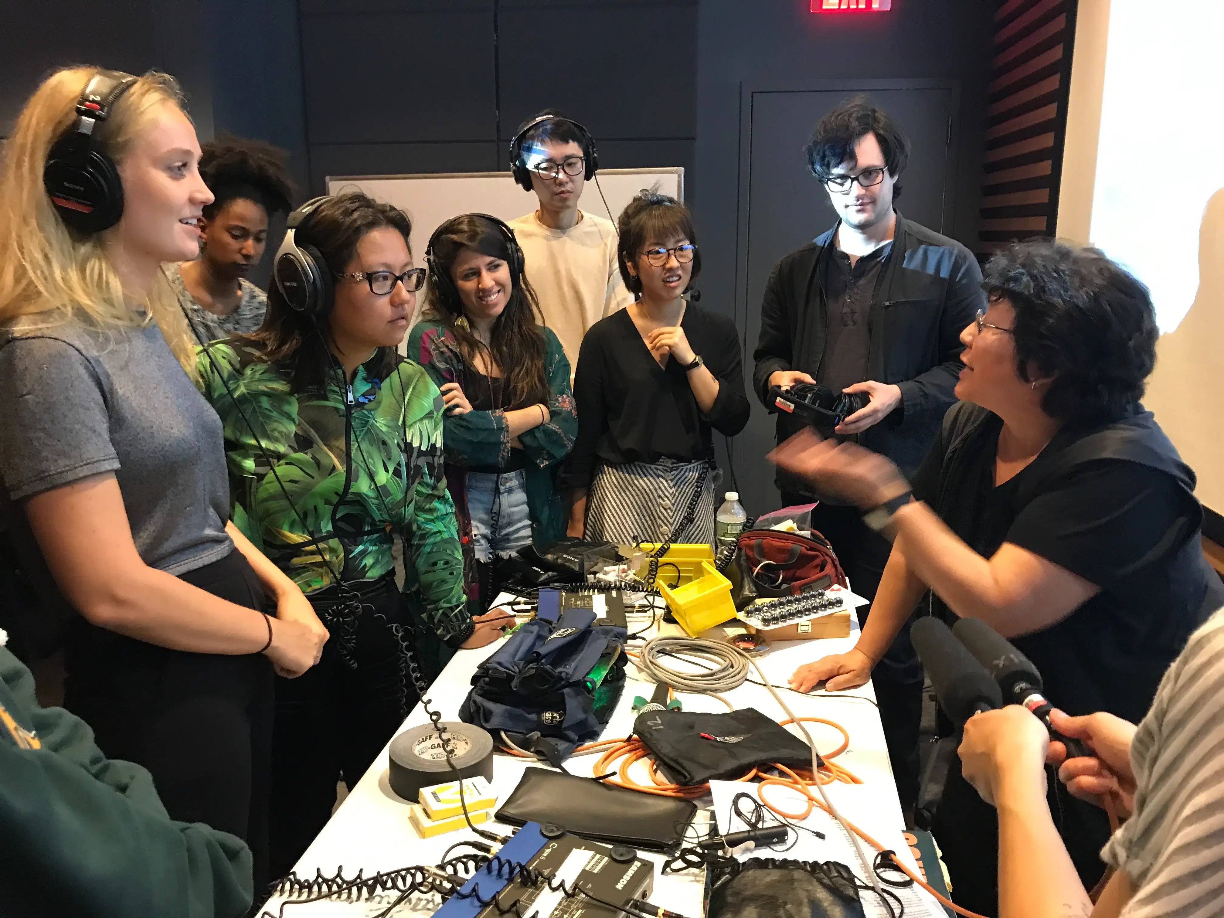Group of students surrounding table full of equipment in Sound Class with Instructor