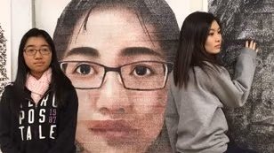 Two girls posing by paintings.