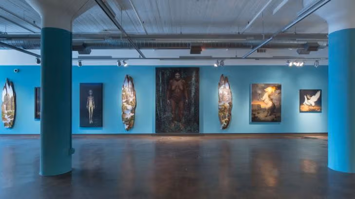 A gallery of pictures displaying an ape in the center . Pillars and walls  painted blue.