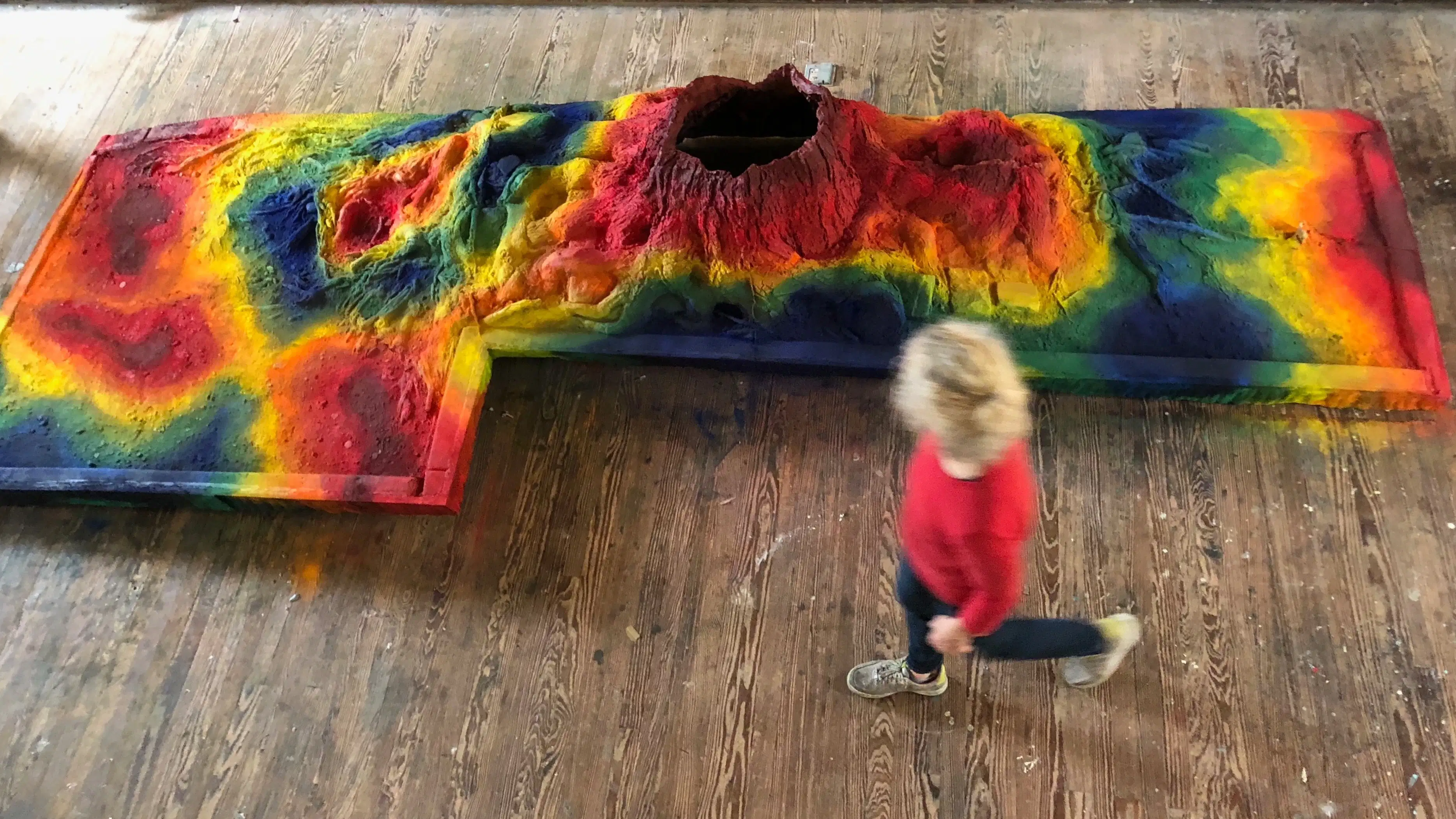 Artist Jude Tallichet walking by her sculpture. Title: Heatmap, 16 feet long, 6 feet wide, two feet tall, reinforced plaster, polyurethane, powdered pigments, 2020