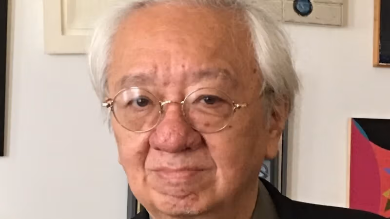 Photo of John Yau in front of wall with art