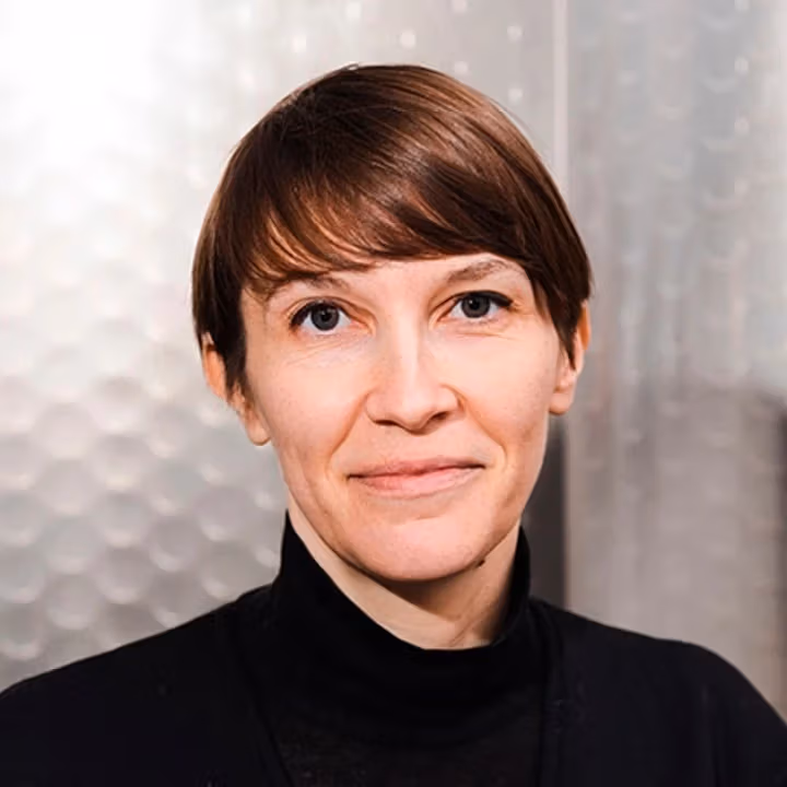 a person with short hair and a black turtleneck look ahead