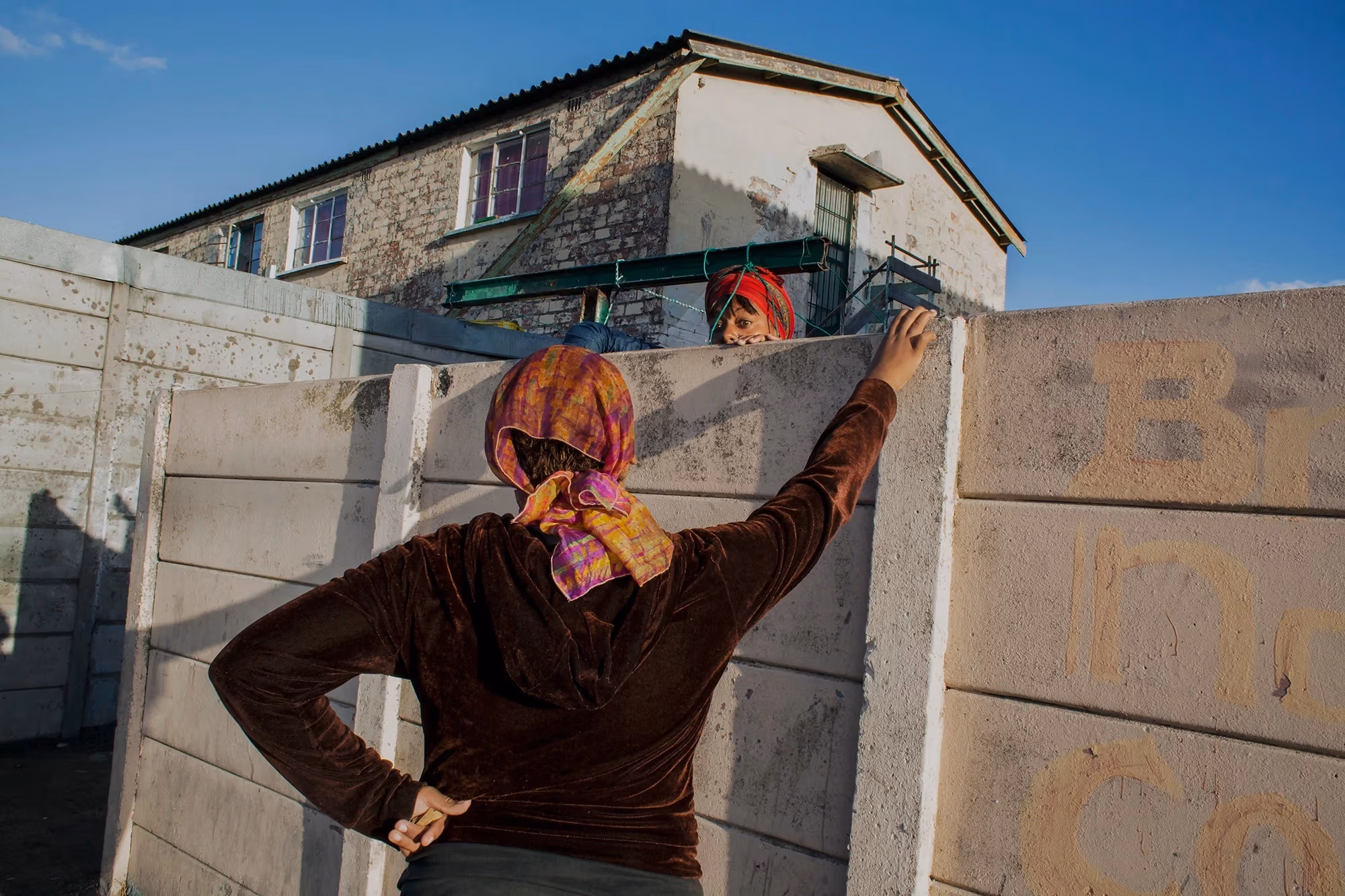 Two women speaking over a concrete wall. 