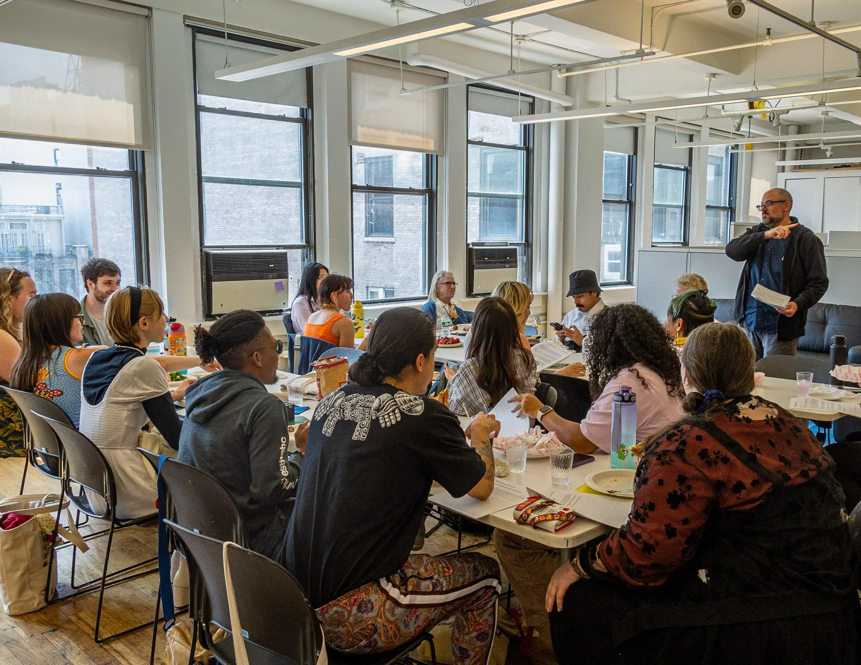 Photo of students sitting around tables in a classroom.