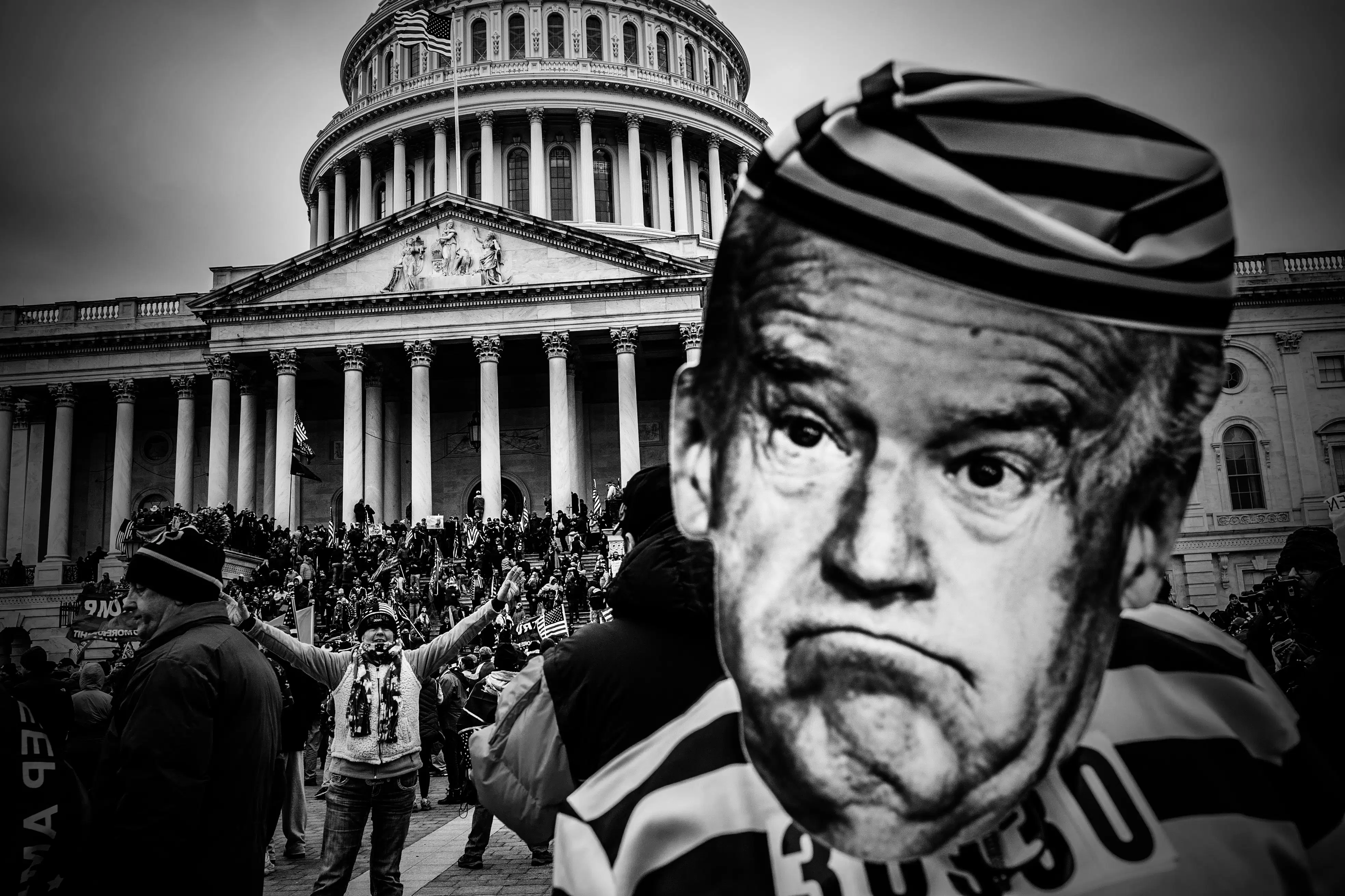 Riot in front of Capitol Hill with Joe Biden's face enlarged to the right. 