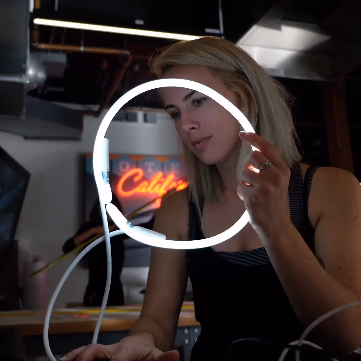 a person holds a white neon light cricle in a studio space
