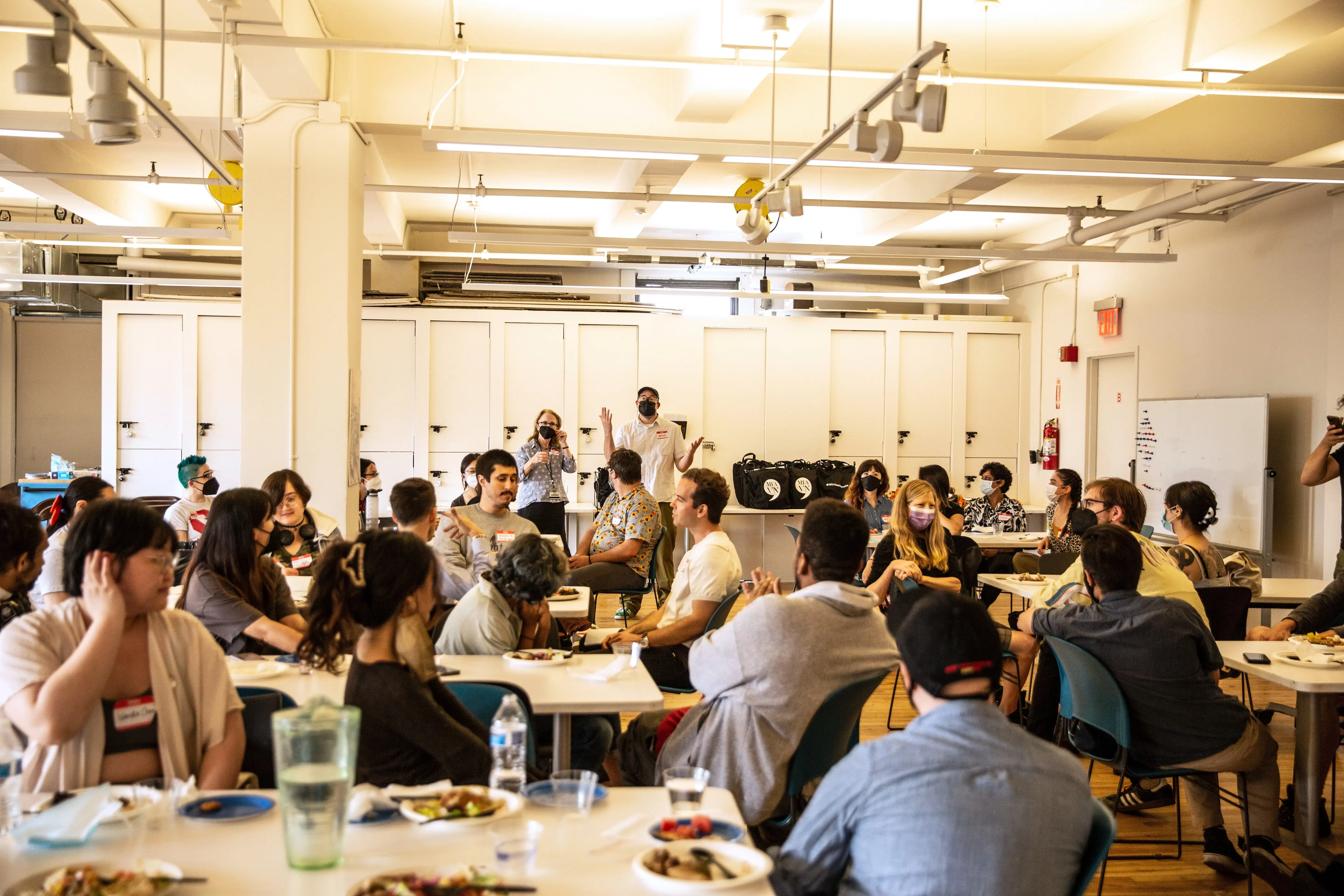 a group of people sit in a classroom while two people at the front lead instruction