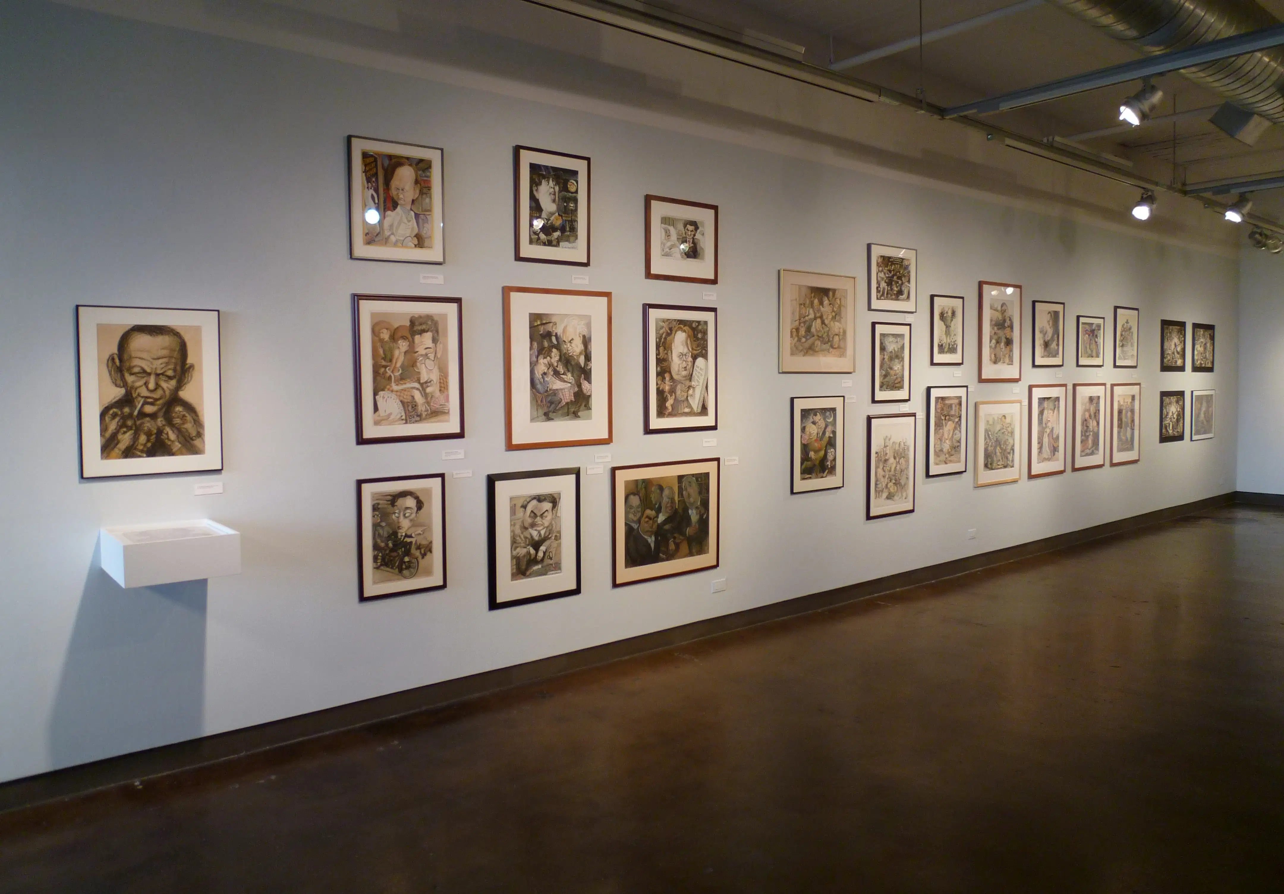 A long gallery wall covered in framed drawings hung salon-style. 
