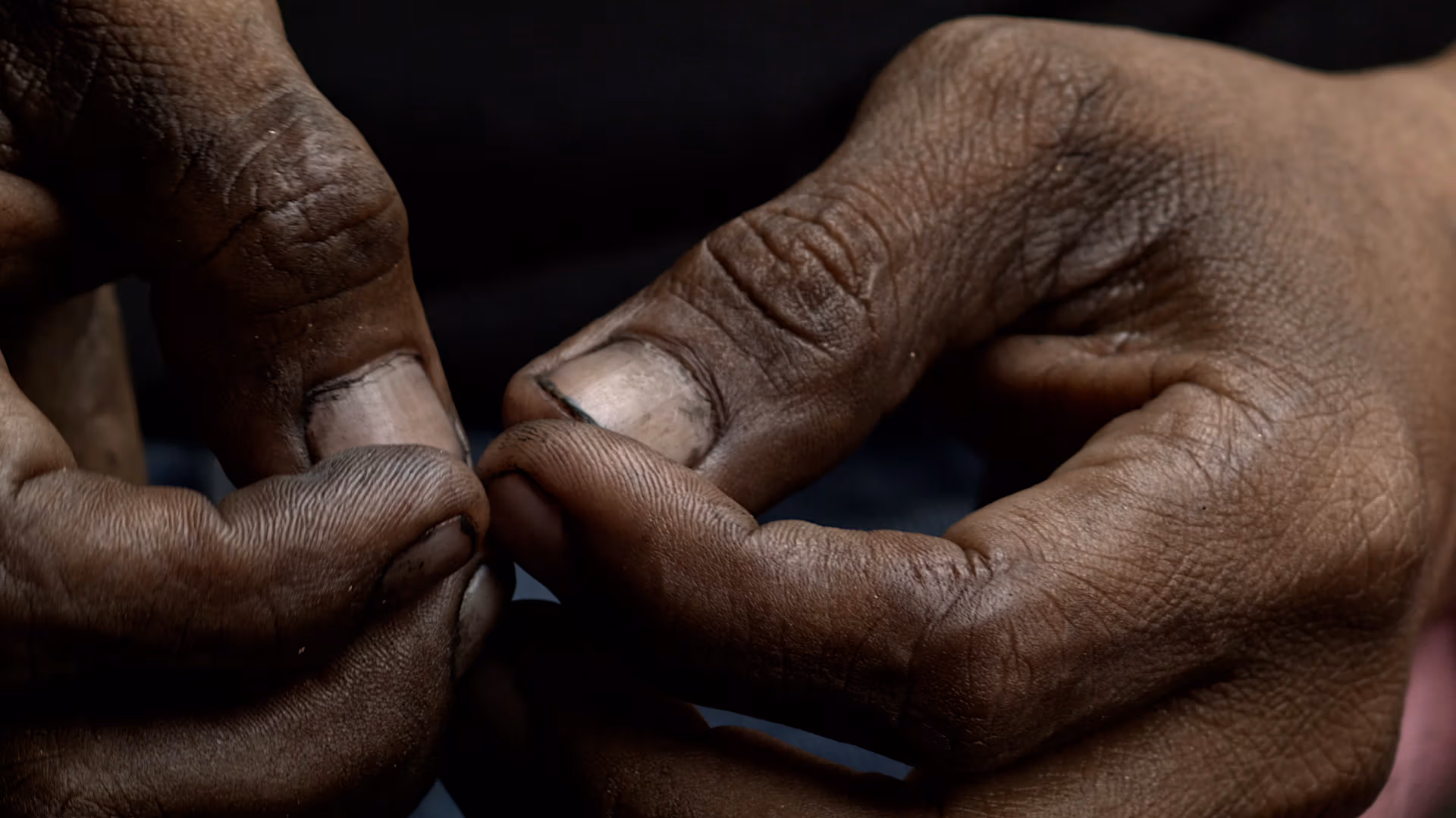 Still from The Mechanics short film, a photo of a pair of curled hands, with some dirt around the fingernails.