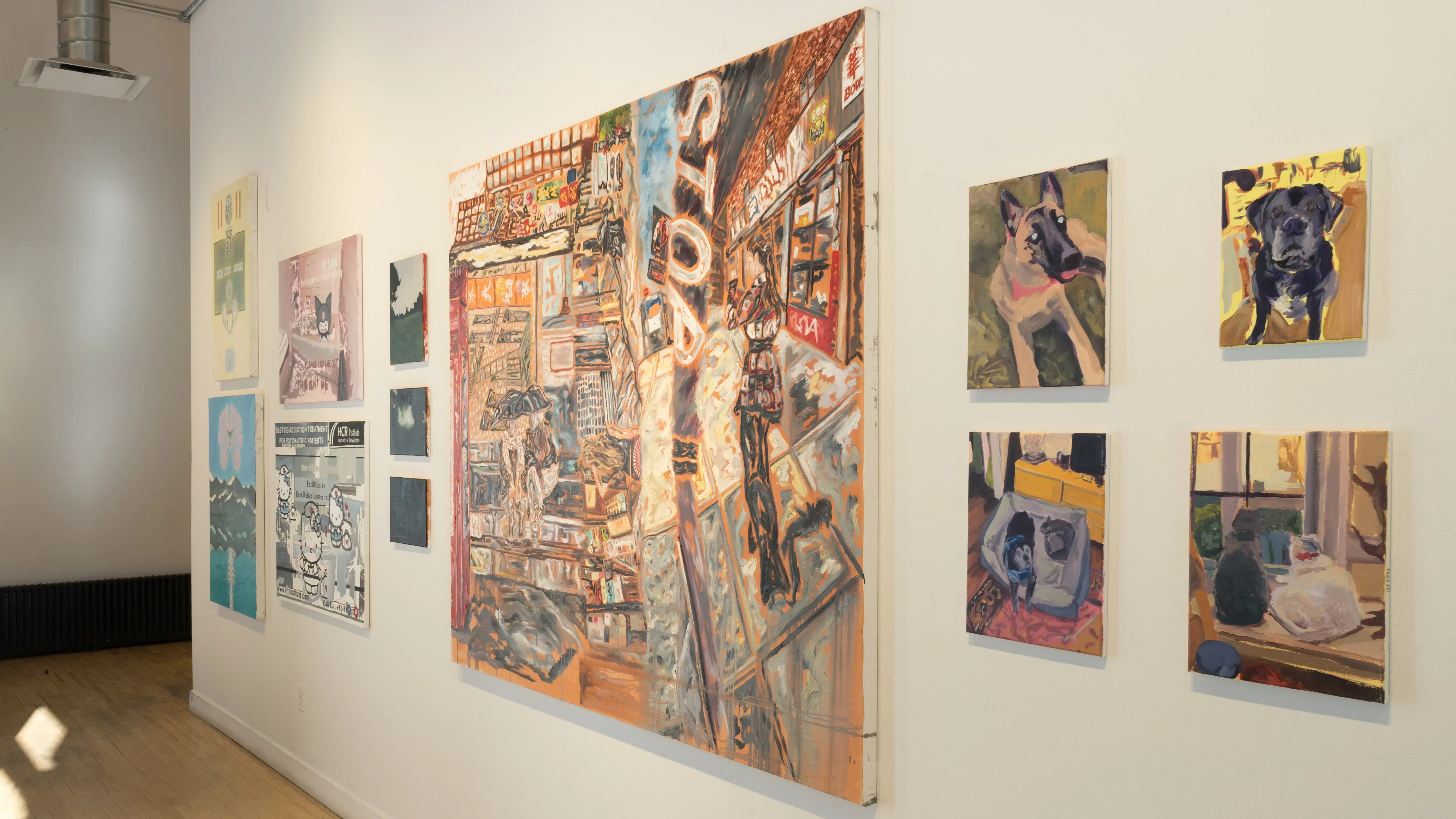 A row of paintings on a gallery wall in many different sizes, ranging from abstract to figurative.