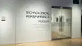 In the gallery alcove, outside of the glass doors, the wall text reads “Technological Perseverance / 2025 Fall Exhibition / MFA Computer Arts.”